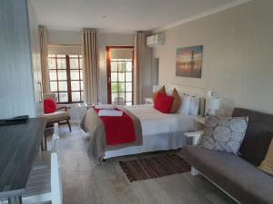 a bedroom with a large white bed and a couch at Outeniqua en Route in George