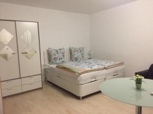 Ein weißes Zimmer mit einem Bett, einem Tisch und einem Tisch. in der Unterkunft Pensionsappartments Blitz in Wiesbaden