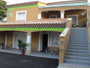 ein Haus mit Treppen, Stühlen und einer Veranda in der Unterkunft Hôtel l'Anvia in Bollène