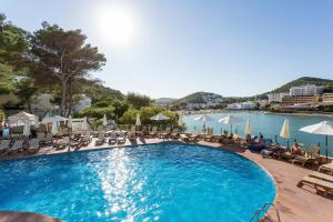 una gran piscina con gente sentada a su alrededor en Palladium Hotel Cala Llonga - Adults Only en Cala Llonga