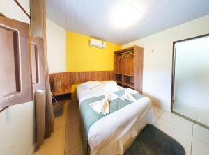 a small room with a bed and a yellow wall at Pousada Cores dos Corais in Maracajaú