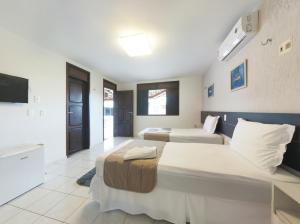 a hotel room with two beds and a television at Pousada Cores dos Corais in Maracajaú