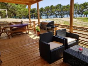 a deck with a grill and chairs and a table at Mobile Homes Aurea Maris - Kamp Dole Živogošće in Živogošće