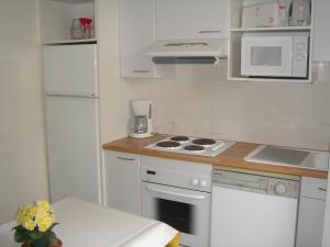 a small kitchen with white appliances and a table at Villa Etche Xuria in Biscarrosse-Plage