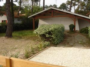 a white garage with a tree in front of it at Villa Etche Xuria in Biscarrosse-Plage