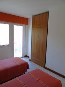 a bedroom with two beds and a cabinet and windows at Villa Valeria in Lignano Sabbiadoro