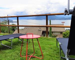 a red table on a balcony with a view of the water at Le Camere Della Vecchia Osteria in Stresa