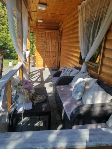 a porch with two couches and a wooden cabin at Lawendowa Weranda in Krasnobród