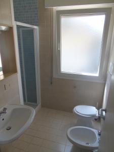 a bathroom with a toilet and a sink and a window at Villa Valeria in Lignano Sabbiadoro