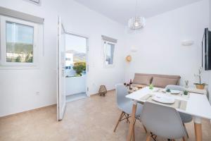 Un comedor blanco con una mesa y sillas blancas. en Agia Anna Apartments, en Parikia