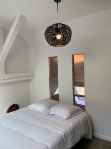 Dormitorio blanco con cama y lámpara colgante en Appart LE COUCOU, en Saint-Hippolyte