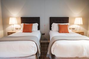 two beds with orange pillows in a room at The Princess Royal in Farnham