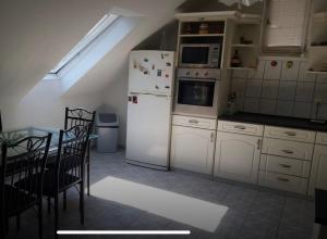 Gabe's Nest في Üröm: مطبخ به أجهزة بيضاء وطاولة وكراسي