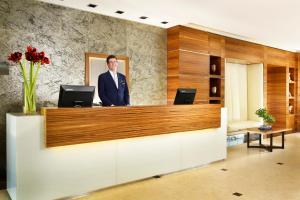 Hotel La Favorita في مانتوفا: رجل في بدلة واقف في مكتب الاستقبال