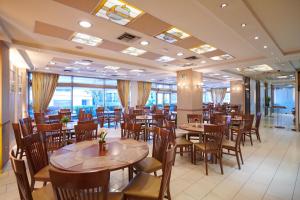 a restaurant with wooden tables and chairs and windows at Crystal City Hotel in Athens