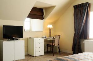 a bedroom with a desk with a television and a bed at Hotel Salons De Vrede in Ichtegem