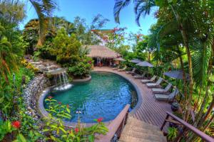 a pool at a resort with chairs and umbrellas at Tulemar in Manuel Antonio