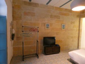 een kamer met een tv en een bakstenen muur bij Zekka Studio in Valletta