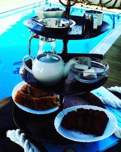 a three tiered tray with plates of food and a tea pot at Castri Village Kythira Quality Resort in Agia Pelagia