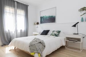 a white bedroom with a white bed and a window at Casa Cosi - Eixample 3 in Barcelona