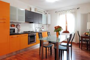 eine Küche mit orangefarbenen Schränken und einem Tisch mit Stühlen in der Unterkunft PadovaResidence Apartments - tra Piazza delle Erbe e il Duomo in Padua