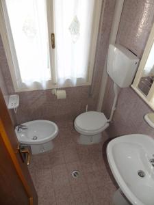 een badkamer met een toilet, een wastafel en een raam bij Residenza Sporting in Lignano Sabbiadoro