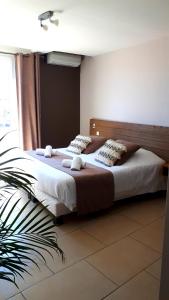 ル・グロー・ダグドにあるHotel Restaurant L'Escaleの大きなベッドと植物のあるベッドルーム1室が備わります。