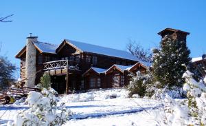 a log cabin in the snow with a christmas tree at Posada La Ensenada in Villa Yacanto