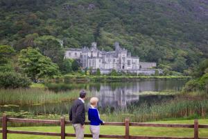 a man and a woman standing in front of a castle at Cottage 139 - Clifden in Clifden