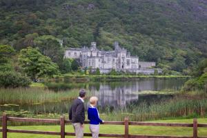 un hombre y una mujer parados frente a un castillo en Cottage 139 - Clifden, en Clifden