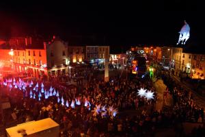 una multitud de personas de pie en una calle por la noche en Cottage 139 - Clifden, en Clifden