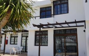 una casa blanca con ventanas negras y una palmera en Las Fresas Apartments, en Puerto Rico de Gran Canaria