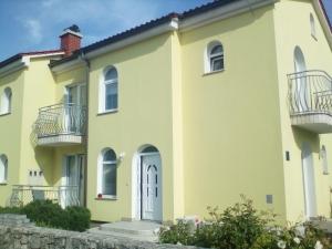 a large yellow house with balconies on it at Ana Rooms in Krk