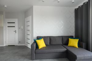 a living room with a gray couch with two yellow pillows at Expo Home Apartment by PinPoint in Łódź