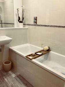 a white bathroom with a bath tub and a sink at Eden Cottage in Frodsham