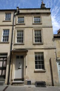 un antiguo edificio de piedra con una puerta y ventanas blancas en Grade II Listed Townhouse in heart of the City - FREE DESIGNATED PARKING en Bath