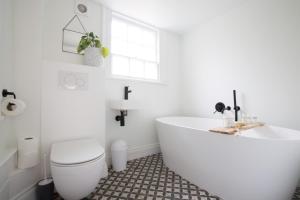 a white bathroom with a tub and a toilet at Grade II Listed Townhouse in heart of the City - FREE DESIGNATED PARKING in Bath