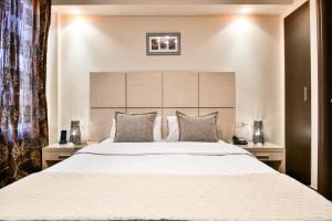 um quarto com uma cama grande com lençóis brancos e almofadas em Athens Way em Atenas