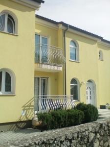 a yellow house with two zebras sitting on a balcony at Ana Rooms in Krk