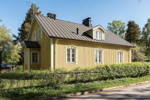 una casa amarilla con techo negro en Villa Härmälä, en Tampere