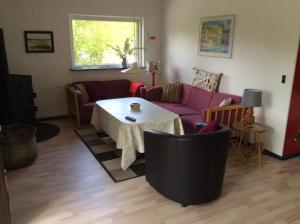 sala de estar con sofá púrpura y mesa en Hummingen Strand 21, en Dannemare