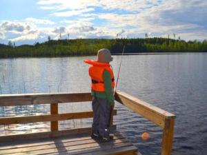 un homme debout sur un quai de pêche sur un lac dans l'établissement Holiday Home Hirviharju by Interhome, à Torsansalo