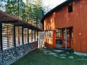 a wooden building with a stone wall next to a building at Holiday Home Huvila hiljaisuus by Interhome in Okka
