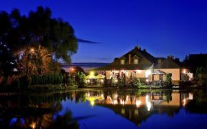 a house with a reflection in the water at night at Hotel Nad Stawem in Bogacica