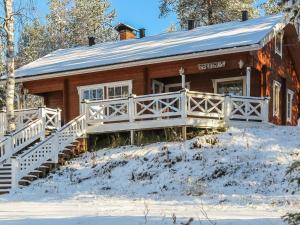 a log cabin in the snow with a white railing at Holiday Home Tokkimus by Interhome in Luosto