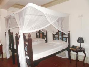 1 dormitorio con 2 camas con mosquiteras en Asmini Palace Hotel, en Zanzíbar