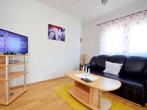 ein Wohnzimmer mit einem schwarzen Ledersofa und einem Tisch in der Unterkunft Apartment Anđa-4 by Interhome in Trogir