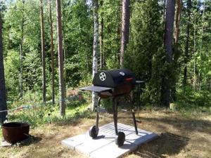 a grill with a hat on it in a forest at Holiday Home Suvikumpu by Interhome in Tuusmäki