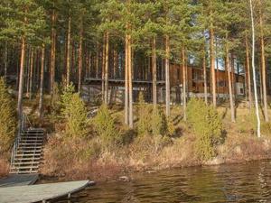 a house on the shore of a lake with trees at Holiday Home Huvila hiljaisuus by Interhome in Okka