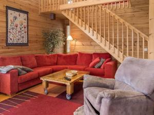ein Wohnzimmer mit einem roten Sofa und einer Treppe in der Unterkunft Holiday Home Syvärinkulta b by Interhome in Tahkovuori